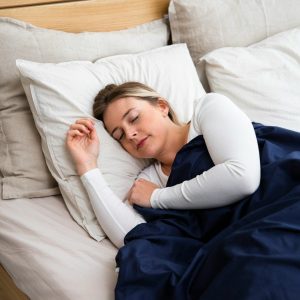 a woman sleeping on a bed with a blue blanket