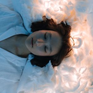 Tranquil portrait of a woman lying peacefully on cloud-like surroundings, evoking calmness.